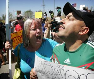 An unidentified protester, left, argues with American citizen Lupillo Rivera, brother of Mexican-American singer Jenni Rivera, right, as three buses carrying 140 immigrants attempt to enter the Murrieta U.S. Border Patrol station for processing on Tuesday, July 1, 2014. (AP Photo/The Press-Enterprise, )IT 